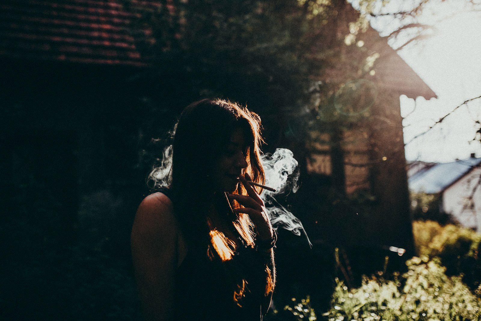 a woman smoking a cigarette in front of a house